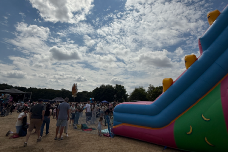 A bouncy castle slide with lots of people stood around it in Tamworth Castle Grounds