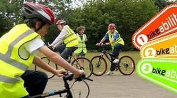 photo of a person wearing a hi-vis waistcoat and bike helmet, on a bike during a training session.