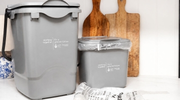 photo of grey small food waste bins next to a wooden chopping board.