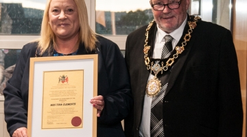 photo of a lady and mayor holding a framed certificate