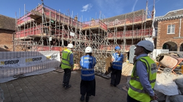 4 people in front of Market St properties in Tamworth with high vis and hard hats as the building is getting restored and has lots of complex scaffolding up around it.